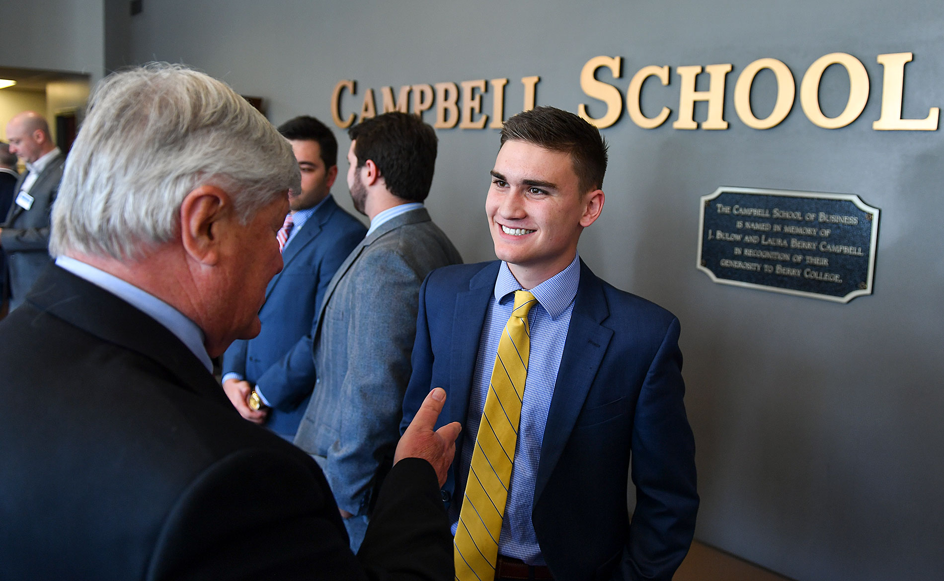 A student in a suit shaking hands with a mentor