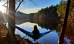 Girl in hammock overlooking reservoir with sunburst